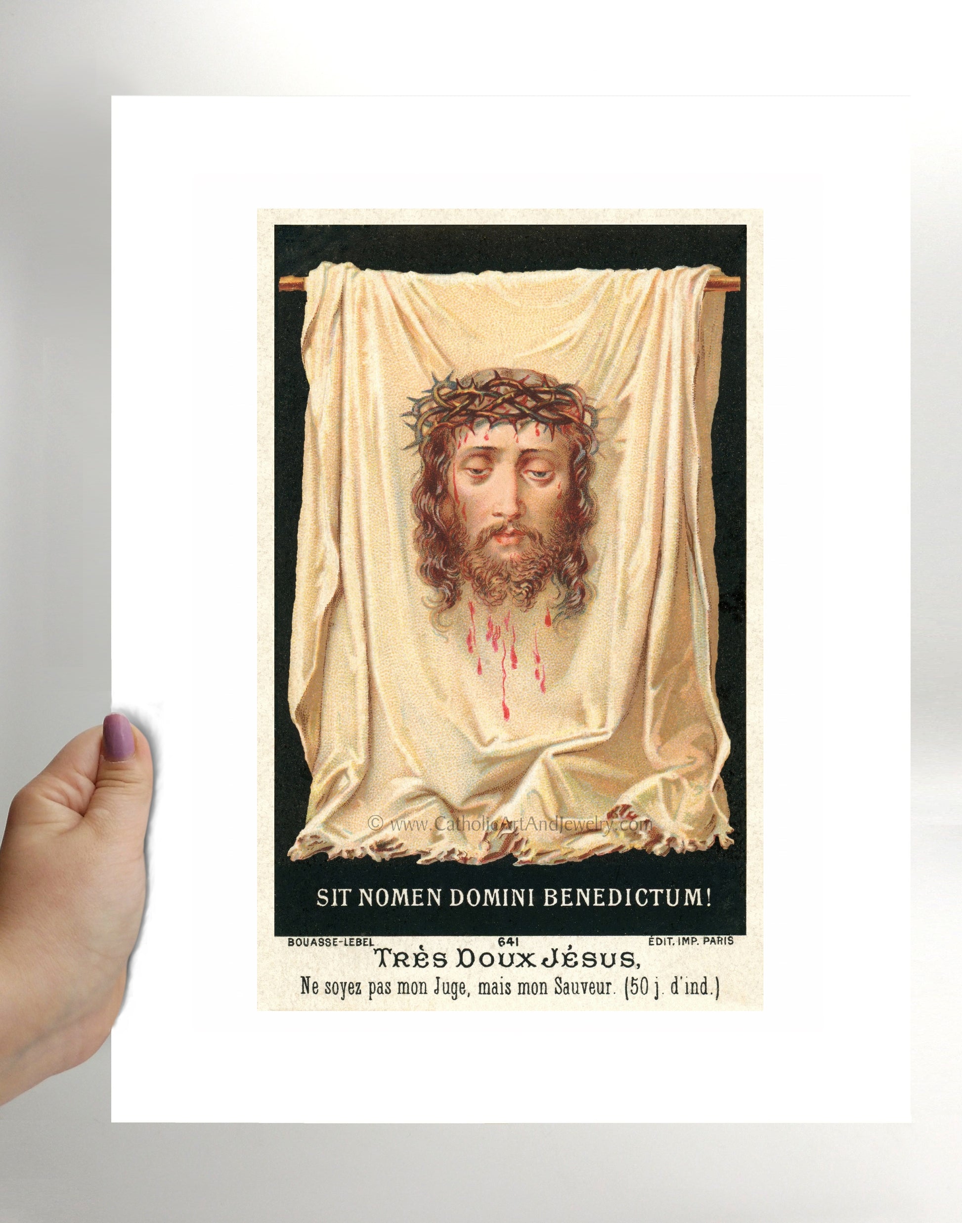 a hand holding a card with a picture of jesus