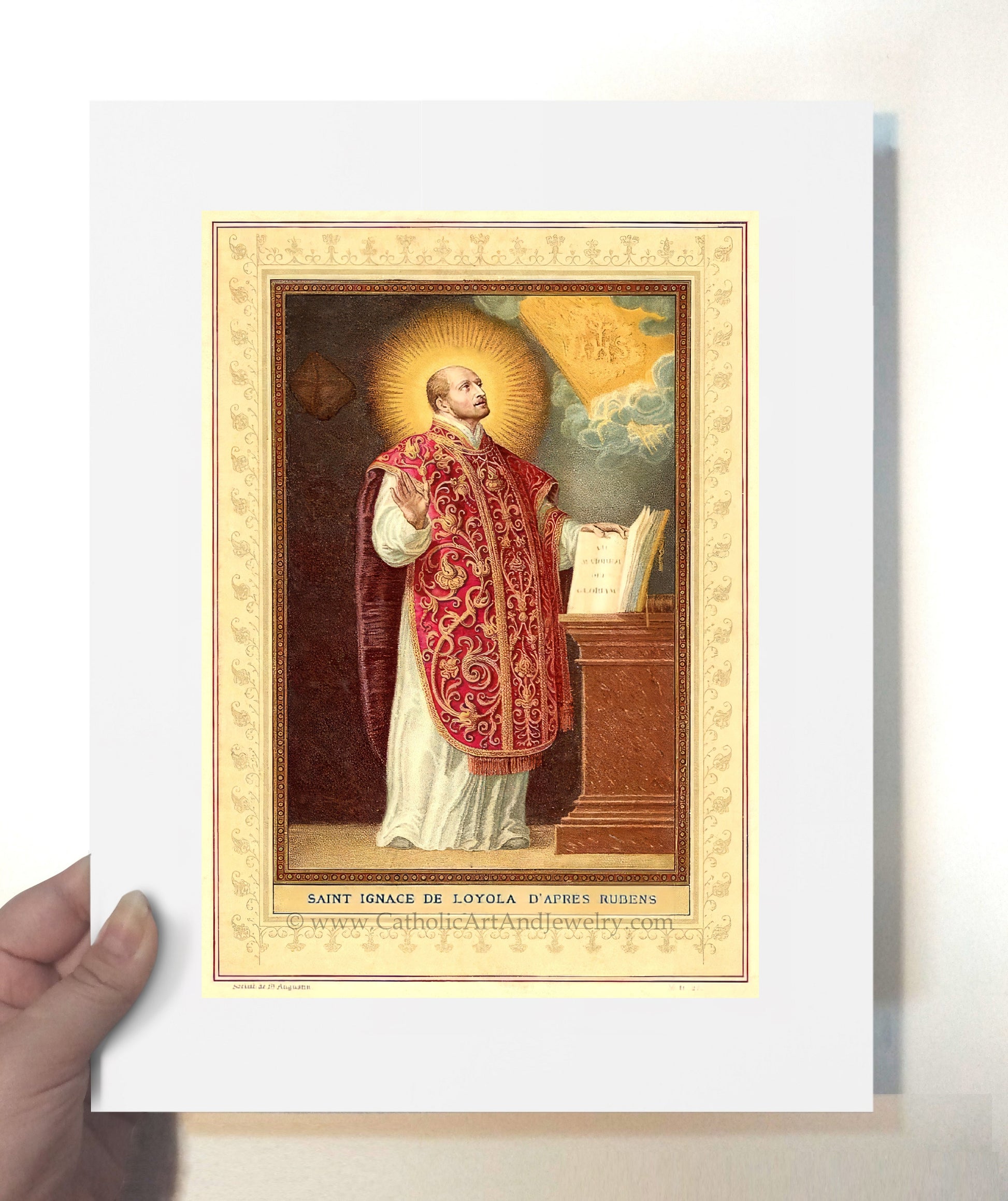 a hand holding a framed picture of a priest