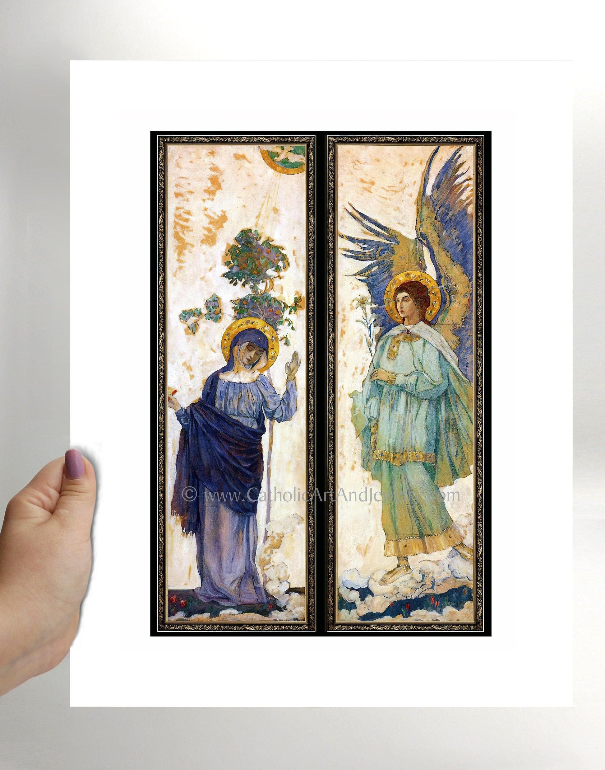 a hand holding a card with two paintings of angels