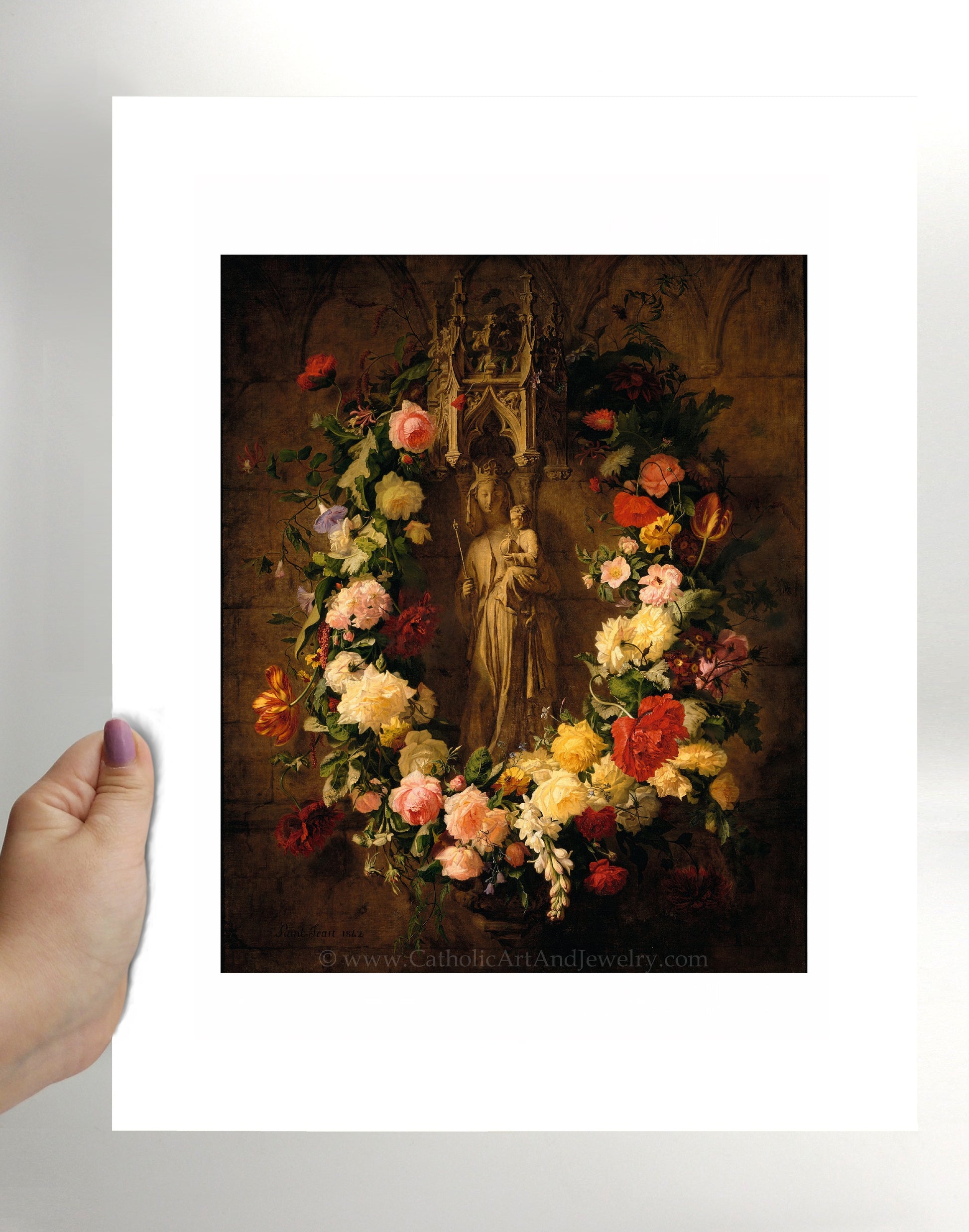 a person holding a picture of a statue in front of a wreath of flowers